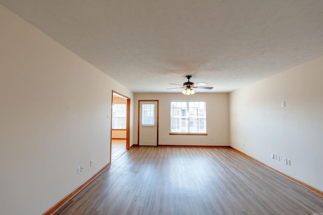 empty room featuring a ceiling fan, wood finished floors, and baseboards