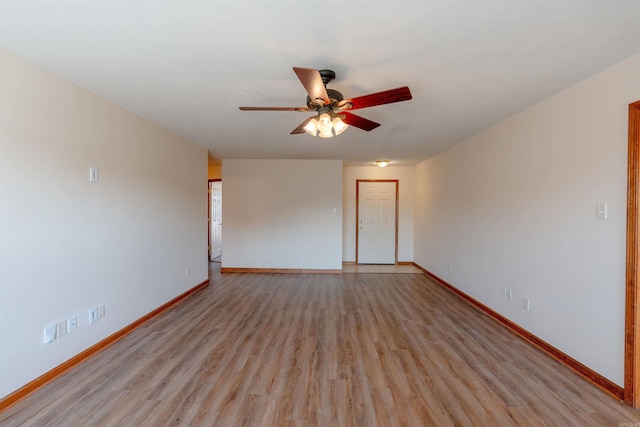 empty room featuring light wood-style flooring, a ceiling fan, and baseboards