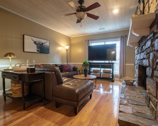 living room featuring ornamental molding, a fireplace, a ceiling fan, and wood finished floors