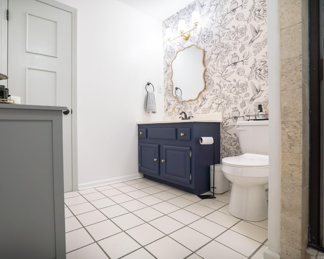 bathroom with toilet, wallpapered walls, tile patterned flooring, baseboards, and vanity