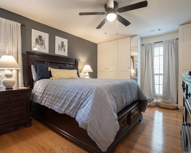 bedroom featuring ceiling fan, visible vents, a closet, and wood finished floors