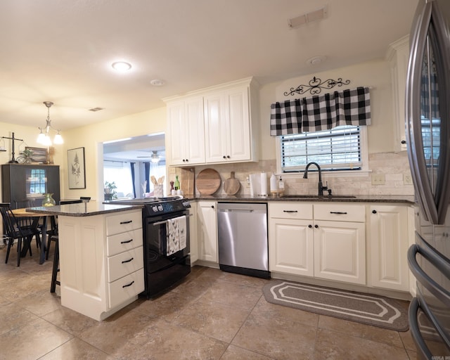 kitchen featuring a peninsula, a sink, stainless steel appliances, white cabinets, and backsplash