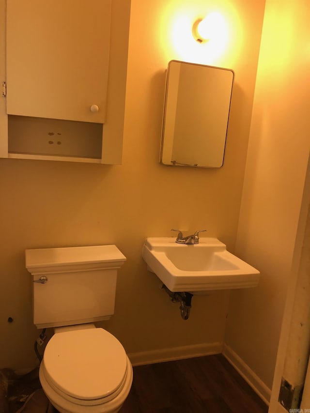 bathroom with a sink, baseboards, toilet, and wood finished floors