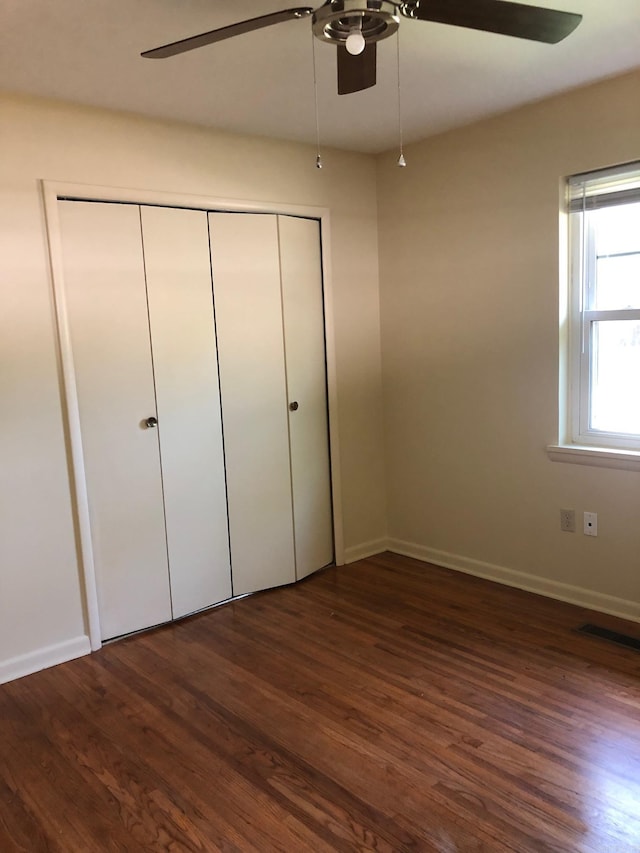 unfurnished bedroom with visible vents, baseboards, a closet, and dark wood finished floors