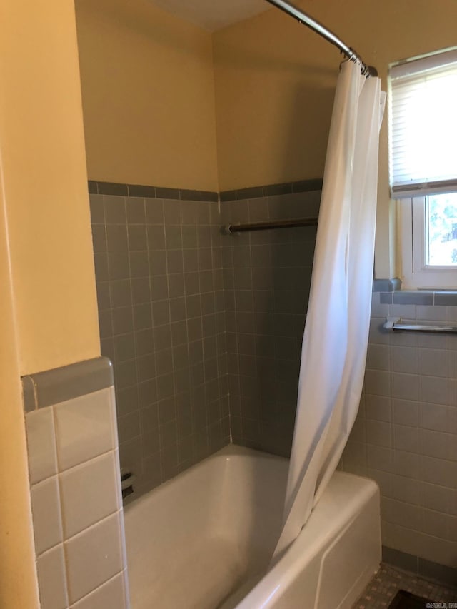 full bathroom with a wainscoted wall, tile walls, and shower / bath combination with curtain