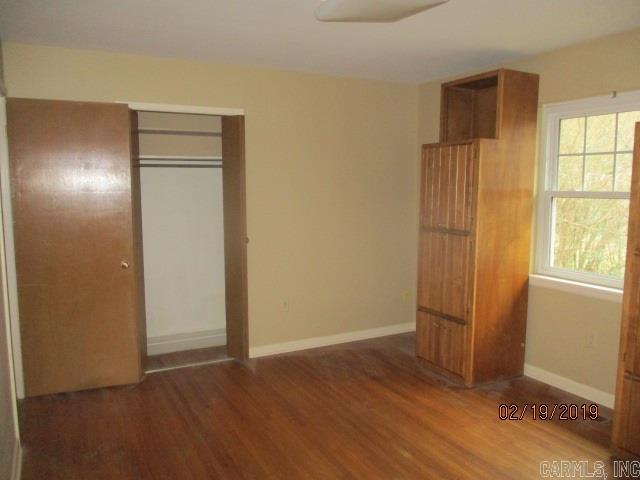 unfurnished bedroom featuring wood finished floors, a closet, and baseboards