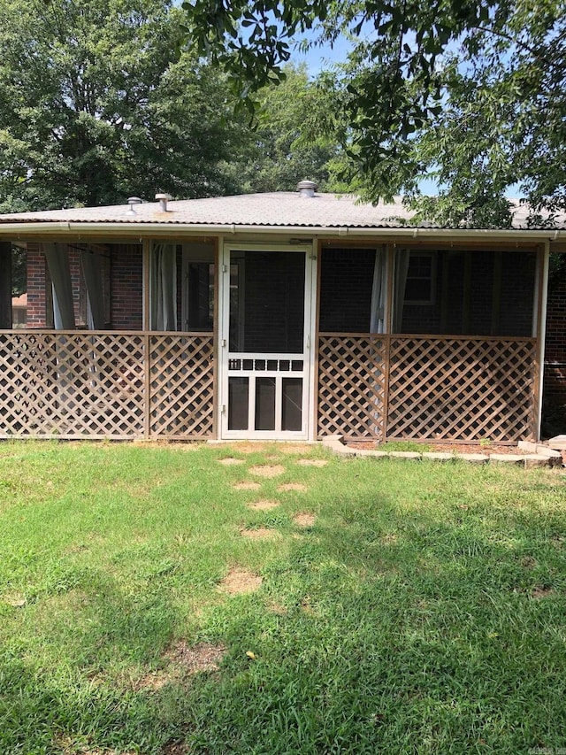 rear view of property with brick siding and a lawn