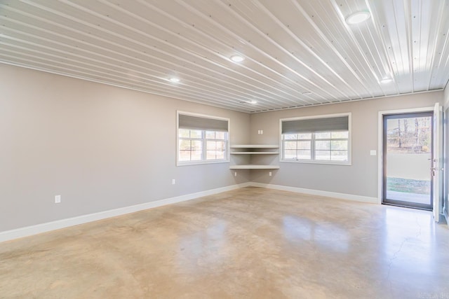 empty room with wood ceiling, concrete flooring, and baseboards