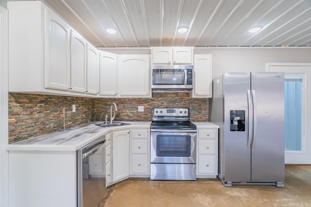 kitchen featuring white cabinetry, concrete flooring, appliances with stainless steel finishes, and a sink