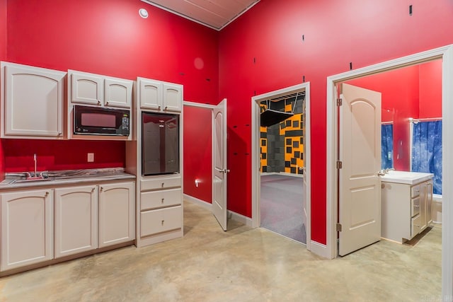 kitchen featuring baseboards, concrete flooring, black microwave, and high vaulted ceiling