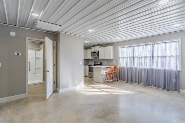 kitchen featuring stainless steel appliances, concrete floors, light countertops, and white cabinetry