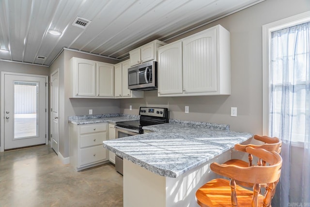 kitchen with white cabinetry, a peninsula, and appliances with stainless steel finishes