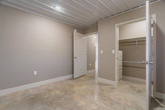 unfurnished bedroom with a closet, baseboards, and concrete floors