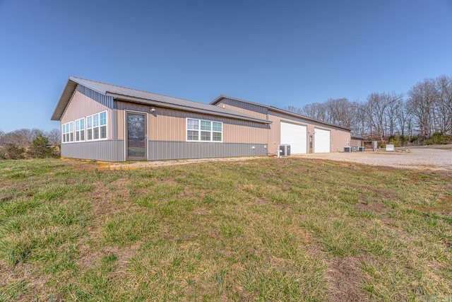 view of side of home featuring central air condition unit, a yard, metal roof, and driveway