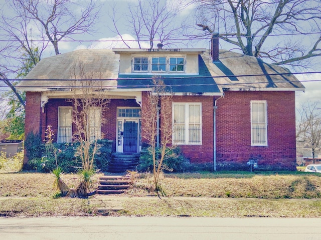 bungalow-style home with a chimney and brick siding