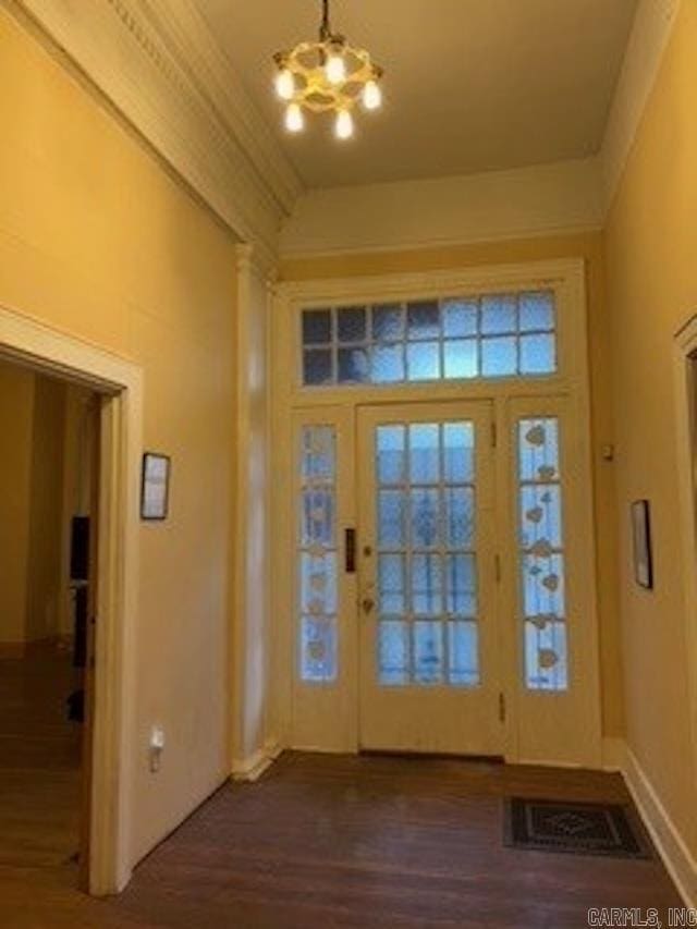foyer entrance featuring an inviting chandelier, dark wood-style flooring, vaulted ceiling, and visible vents