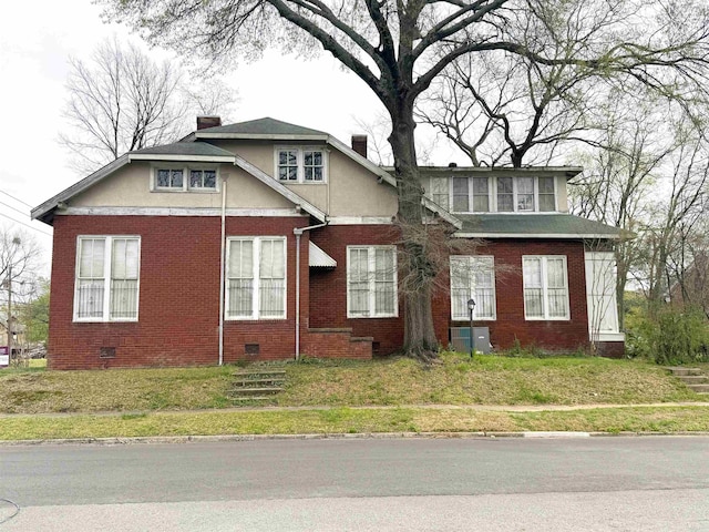 view of front facade featuring stucco siding, a chimney, crawl space, and brick siding