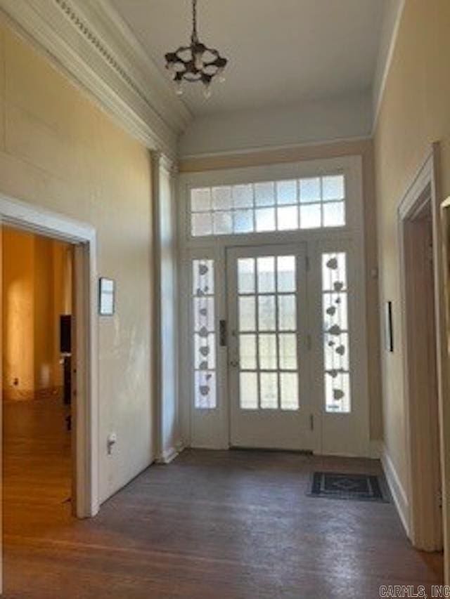 entryway with crown molding, high vaulted ceiling, wood finished floors, and a notable chandelier