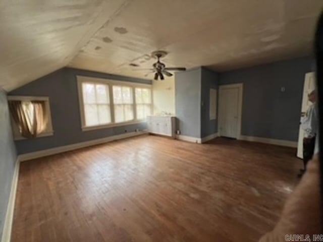 unfurnished living room with baseboards, ceiling fan, wood finished floors, and vaulted ceiling