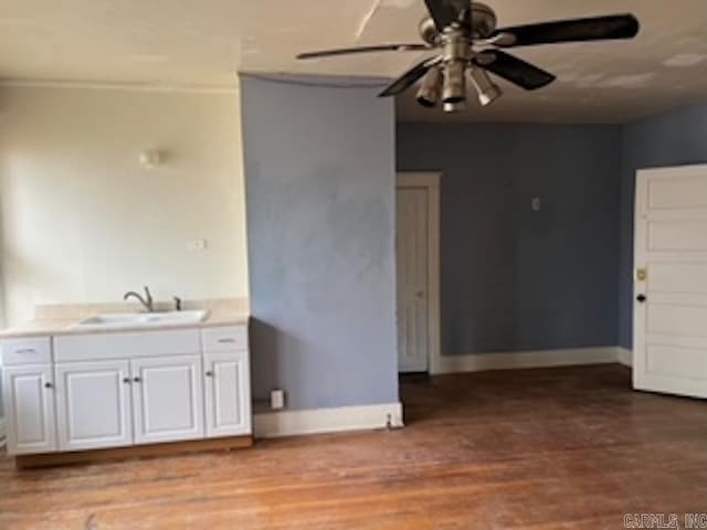 kitchen with light wood-style flooring, baseboards, ceiling fan, white cabinetry, and a sink