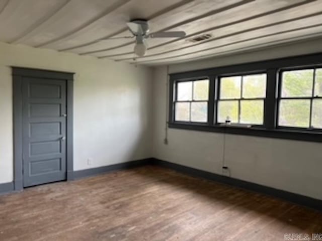 spare room with baseboards, dark wood-style flooring, a ceiling fan, and beamed ceiling