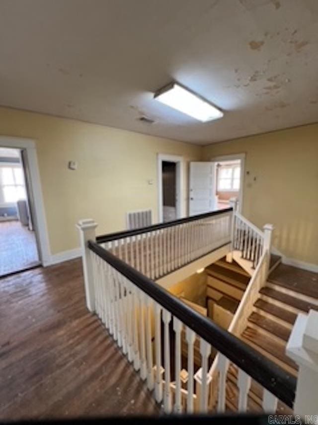 stairway featuring baseboards, visible vents, wood finished floors, and plenty of natural light