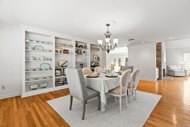 dining area with light wood-type flooring, visible vents, crown molding, baseboards, and a chandelier