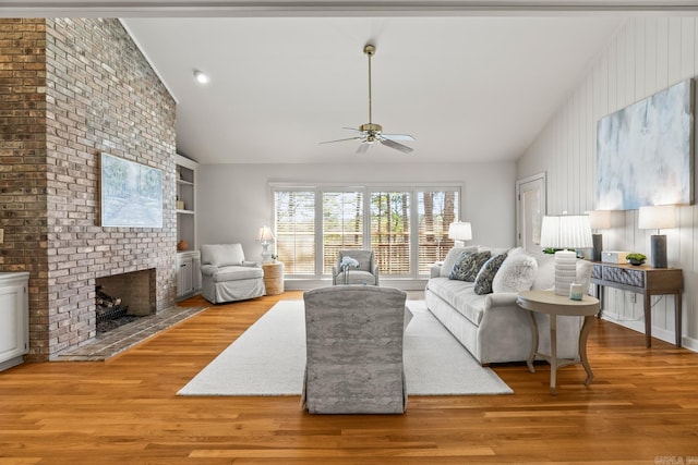 living room featuring built in features, wood finished floors, high vaulted ceiling, a fireplace, and ceiling fan