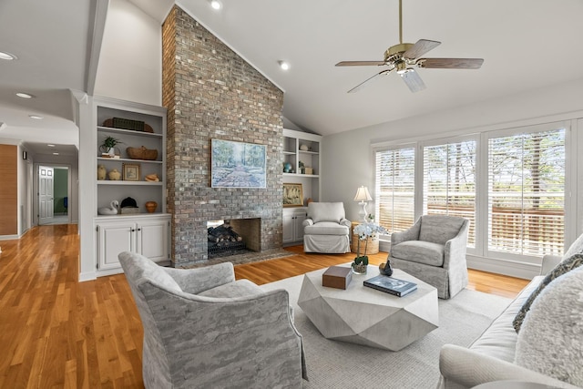 living area featuring a brick fireplace, light wood finished floors, a wealth of natural light, and built in features