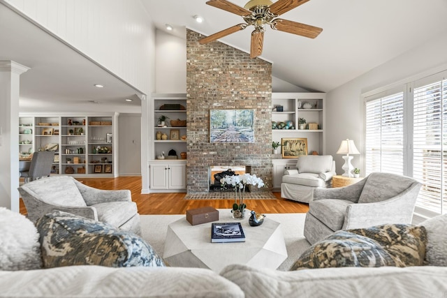 living area featuring built in shelves, a fireplace, ceiling fan, and wood finished floors