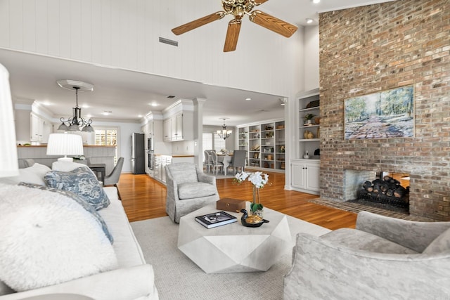 living room with light wood-type flooring, visible vents, a fireplace, and crown molding