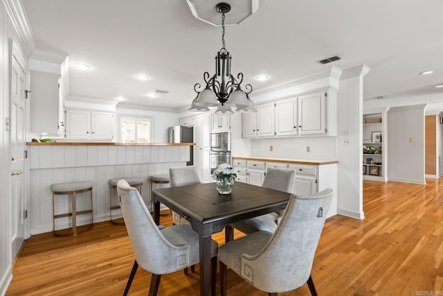 dining area featuring visible vents, baseboards, recessed lighting, light wood-style floors, and crown molding