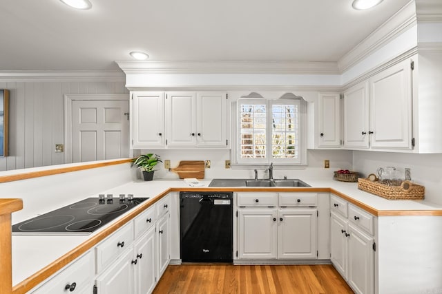 kitchen with light countertops, ornamental molding, light wood-style flooring, black appliances, and a sink