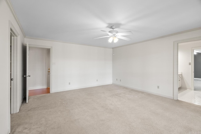 unfurnished bedroom with baseboards, light colored carpet, ornamental molding, ensuite bathroom, and a ceiling fan