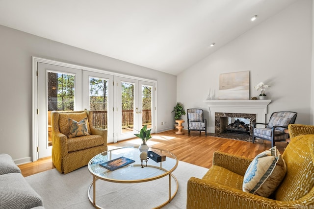 living area with wood finished floors, baseboards, high vaulted ceiling, recessed lighting, and a high end fireplace