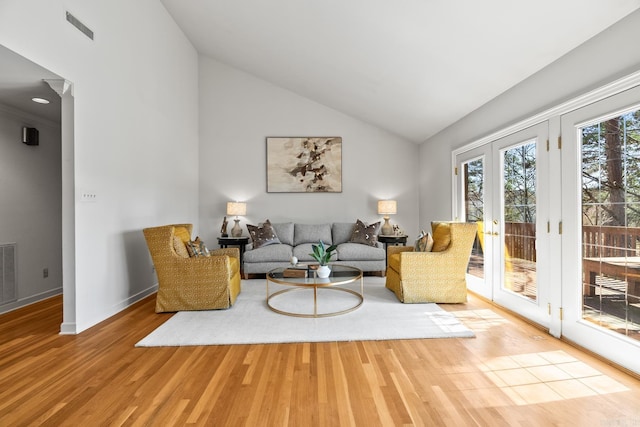 living area with visible vents, wood finished floors, vaulted ceiling, and french doors