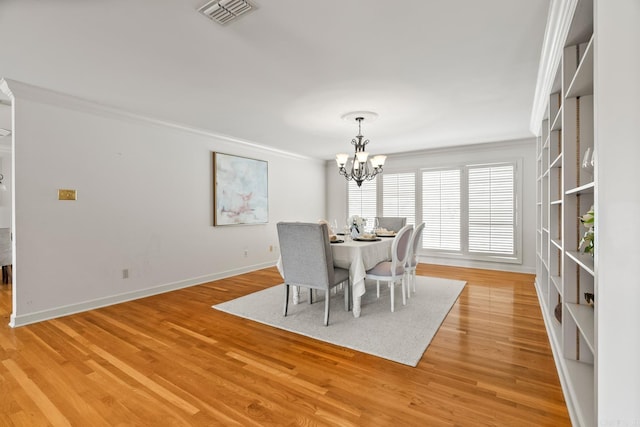 dining room with baseboards, visible vents, an inviting chandelier, ornamental molding, and light wood-style floors