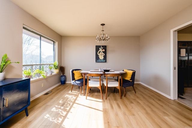 dining room featuring visible vents, baseboards, a notable chandelier, and light wood finished floors