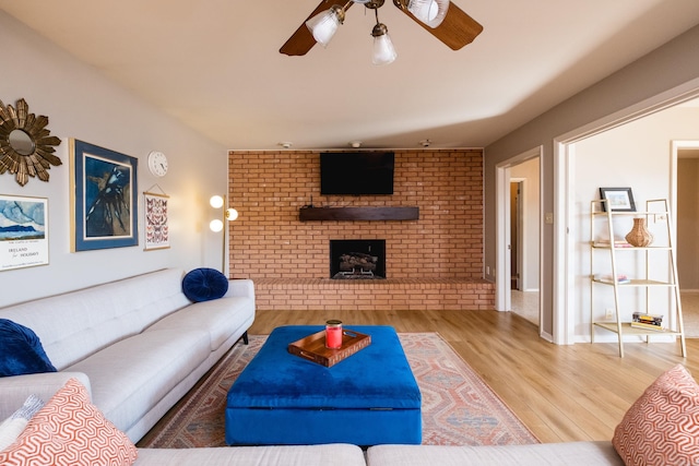 living area featuring a fireplace, wood finished floors, and a ceiling fan