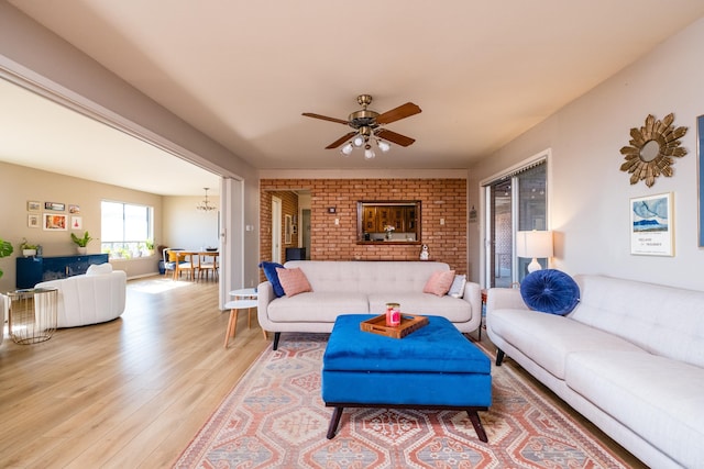 living room with light wood-style flooring and ceiling fan with notable chandelier