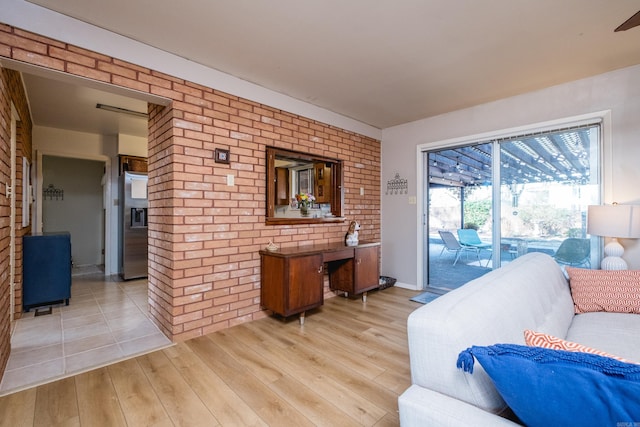 living area featuring light wood-style flooring and brick wall