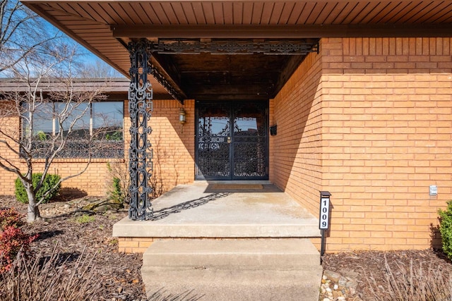 view of exterior entry with brick siding and french doors