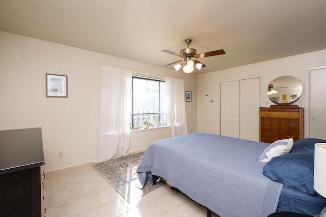 bedroom with baseboards, two closets, light tile patterned flooring, and a ceiling fan