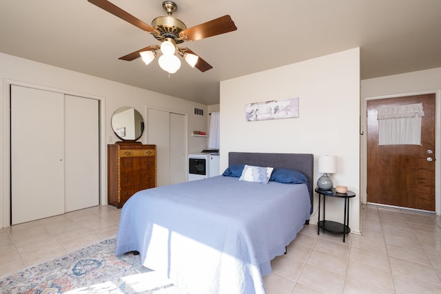 bedroom with light tile patterned floors, visible vents, multiple closets, and a ceiling fan