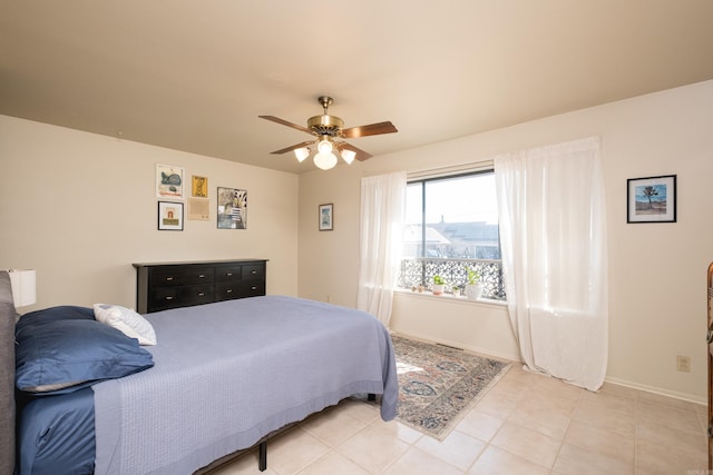 bedroom featuring light tile patterned floors, baseboards, and ceiling fan