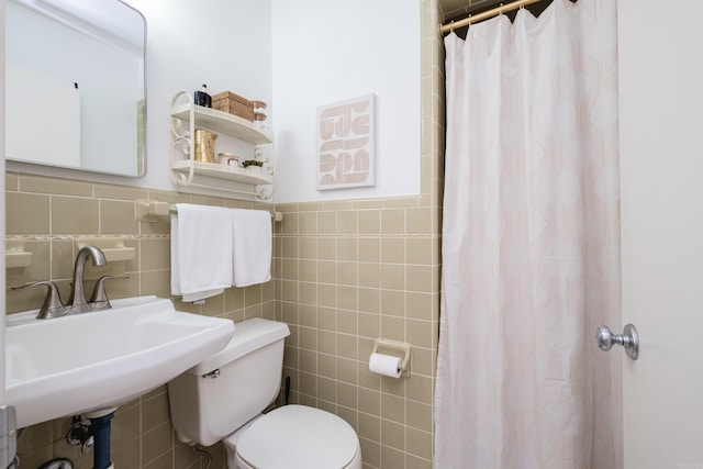 bathroom featuring a shower with shower curtain, toilet, tile walls, and a sink