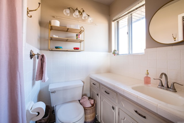 bathroom with tile walls, a wainscoted wall, toilet, and vanity