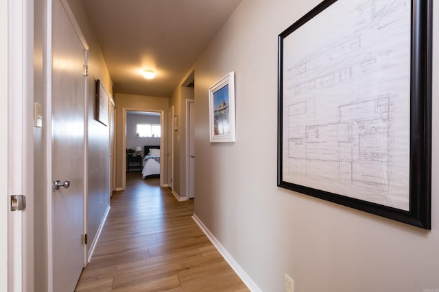 hall with light wood-style floors and baseboards