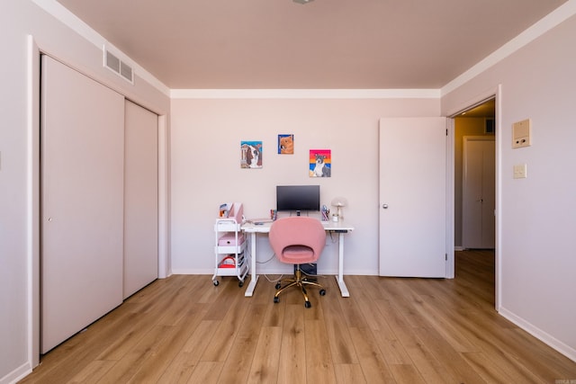 office space featuring visible vents, light wood-style flooring, baseboards, and ornamental molding