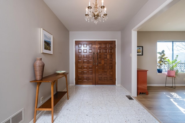 foyer entrance with a notable chandelier, visible vents, tile patterned floors, and baseboards